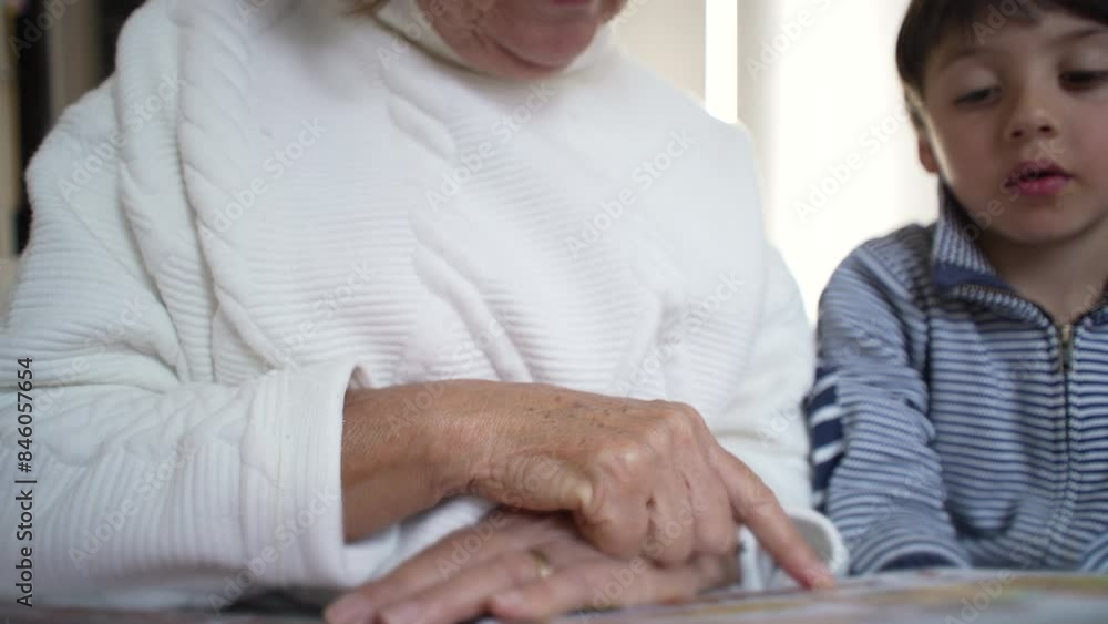 Close-up of an elderly woman's hand pointing at a book page while her grandson attentively follows along, moment of shared learning and intergenerational connection, storytelling Close-up of an elderly woman's hand pointing at a book page while her grandson attentively follows along, moment of shared learning and intergenerational connection, storytelling