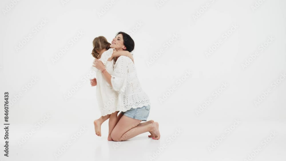 Happy mother and daughter playing and having fun on a white background. Concept of a happy family, motherhood, style and fashion. Happy mother and daughter playing and having fun on a white background. Concept of a happy family, motherhood, style and fashion.