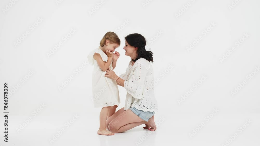 Happy mother and daughter playing and having fun on a white background. Concept of a happy family, motherhood, style and fashion. Happy mother and daughter playing and having fun on a white background. Concept of a happy family, motherhood, style and fashion.