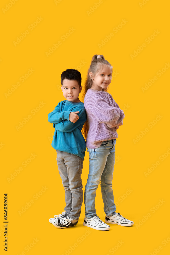 Cute little children in knitted sweaters on yellow background Cute little children in knitted sweaters on yellow background