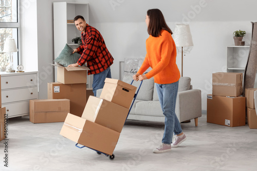 Happy young couple with boxes in room on moving day photo