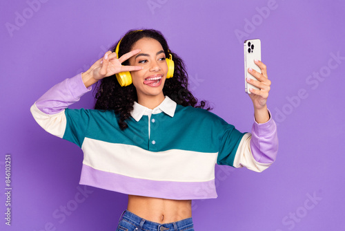 Photo of nice young girl make selfie v-sign wear shirt isolated on violet color background photo