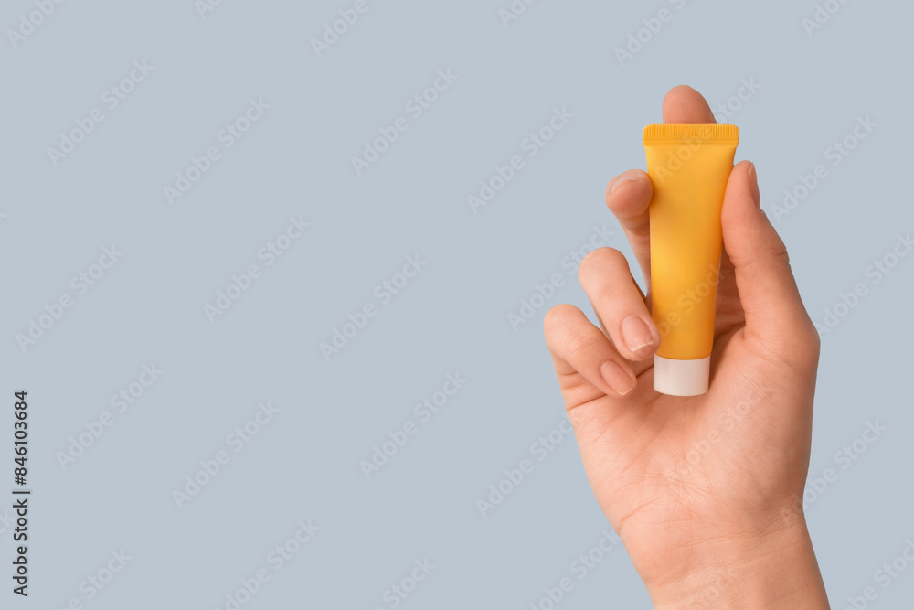 Female hand with tube of natural cream against color background, closeup Female hand with tube of natural cream against color background, closeup