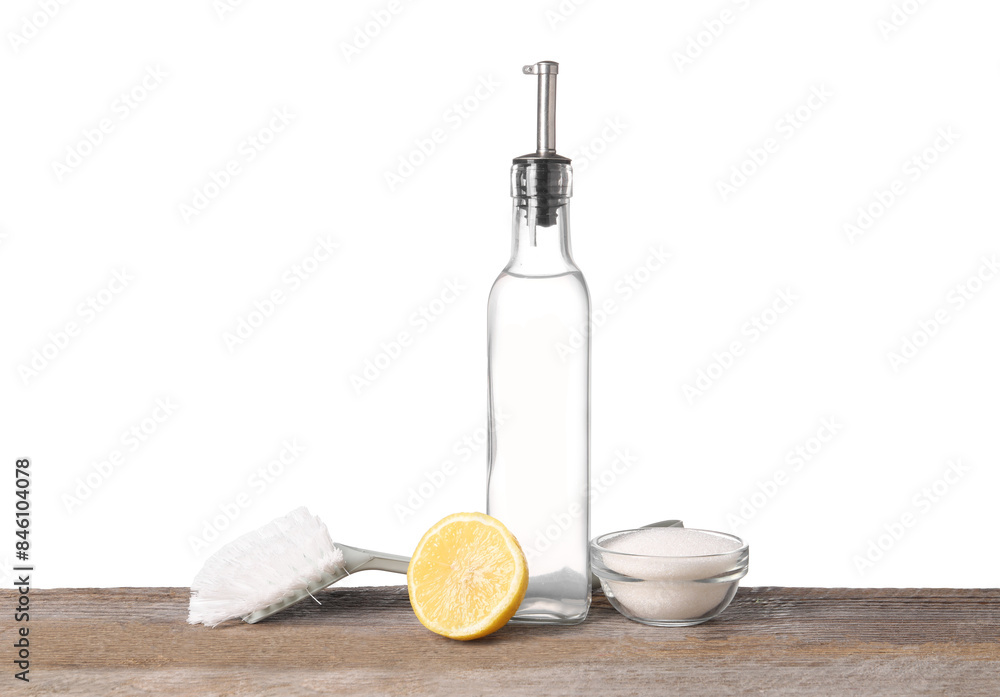 Natural cleaning products. Vinegar in bottle, baking soda, lemon and brush on wooden table against white background Natural cleaning products. Vinegar in bottle, baking soda, lemon and brush on wooden table against white background