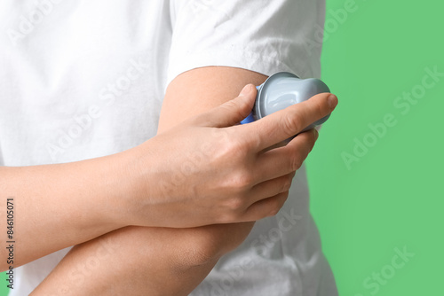 Foto Woman with glucose sensor for measuring blood sugar level and applicator on green background, closeup