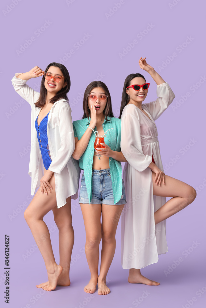 Obraz premium Beautiful young women with glass of cocktail on lilac background. Summer party