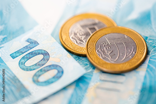 Real - BRL, moeda corrente do Brasil. Moedas de 1 Real e cédulas bancárias de 100 reais em fotografia macro. Economia brasileira, negócios e finanças.