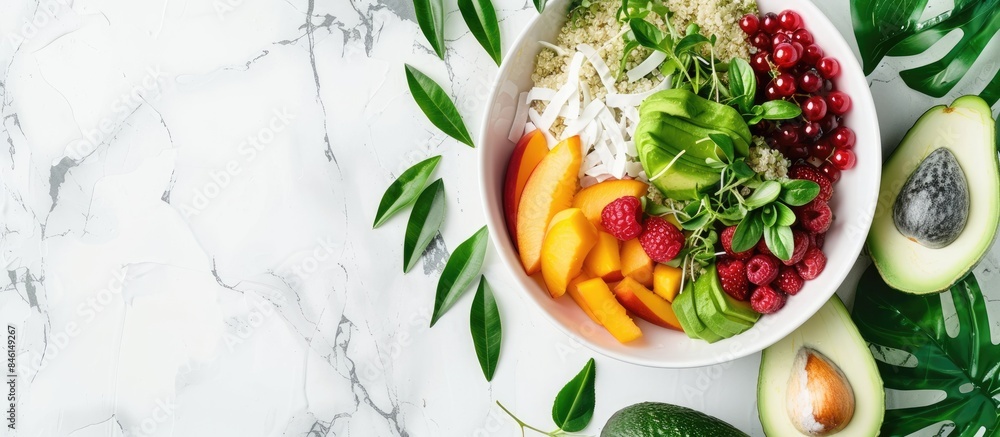Summer Buddha bowl with quinoa, peach, micro greens, avocado, berries, coconut, and melon on a light marble background adorned with tropical leaves. Summer Buddha bowl with quinoa, peach, micro greens, avocado, berries, coconut, and melon on a light marble background adorned with tropical leaves.