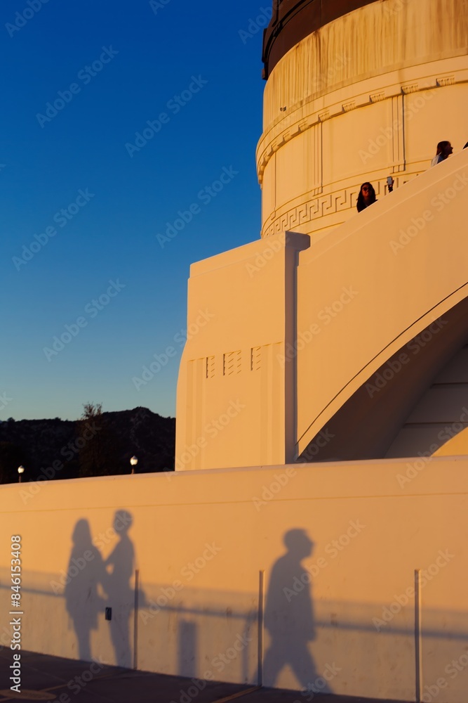 Fototapeta premium Abstract shapes of peoples shadows cast onto the building of the Griffith Observatory at sunset, Los angeles, California, USA.