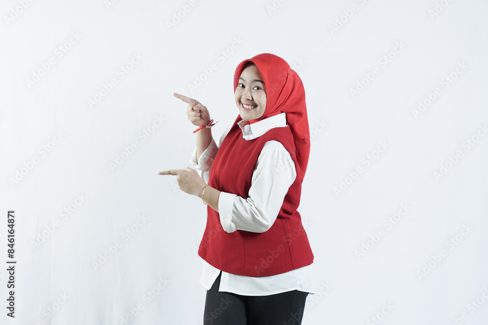 Asian hijab woman in looks happy in Indonesian independence day outfit. the woman raised her hand and pointed to the upper side of the side Asian hijab woman in looks happy in Indonesian independence day outfit. the woman raised her hand and pointed to the upper side of the side