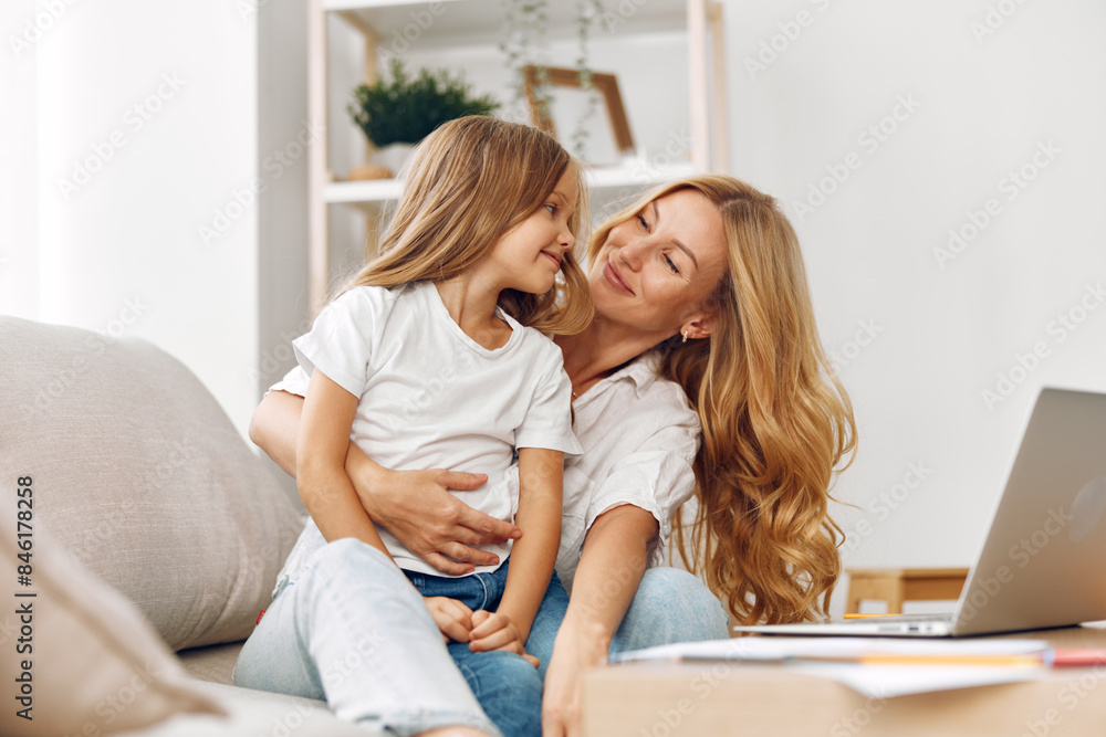 Mother and daughter sharing quality time on the couch while browsing the internet together on a laptop Mother and daughter sharing quality time on the couch while browsing the internet together on a laptop