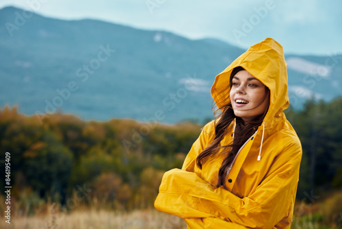 Woman in a yellow raincoat enjoying the peaceful beauty of nature with mountains in the background © SHOTPRIME STUDIO
