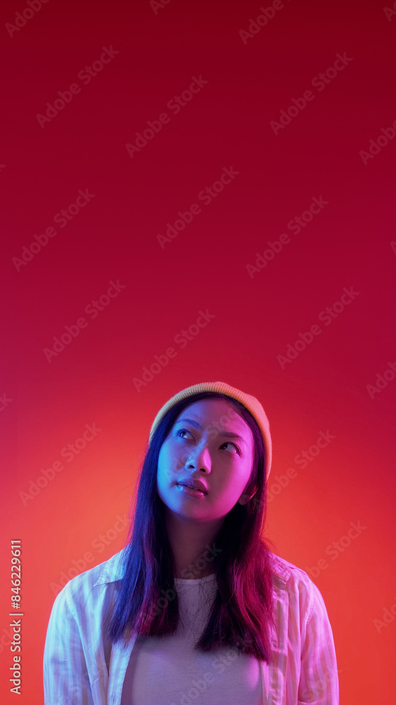 Confusing offer. Choosing solution. Blue pink color neon light puzzled pensive woman analyzing problem isolated on red empty space background. Confusing offer. Choosing solution. Blue pink color neon light puzzled pensive woman analyzing problem isolated on red empty space background.