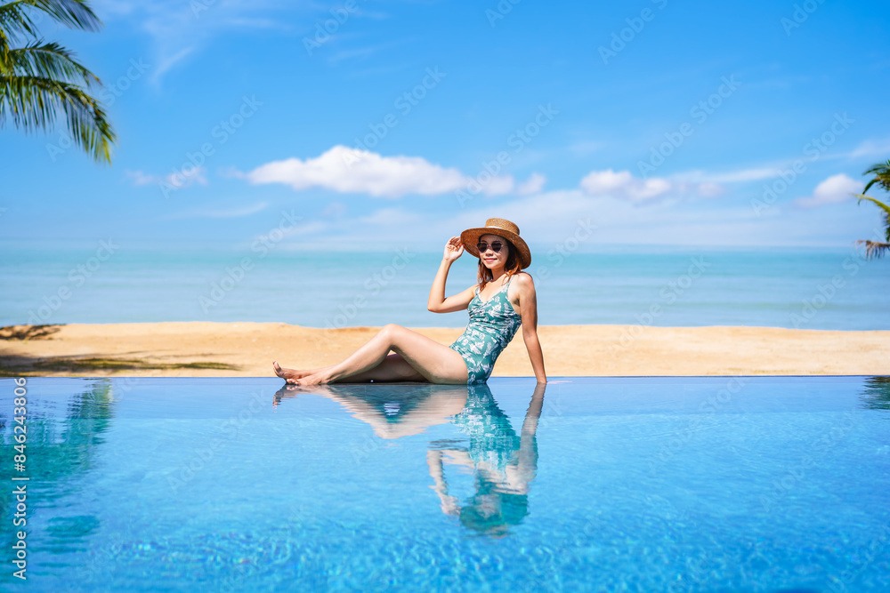 Young woman traveler relaxing and enjoying by a tropical resort pool while traveling for summer vacation, Travel concept Young woman traveler relaxing and enjoying by a tropical resort pool while traveling for summer vacation, Travel concept