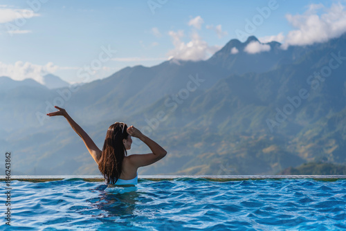 Canvas Print Young woman traveler relaxing in sky pool and looking at the beautiful nature la