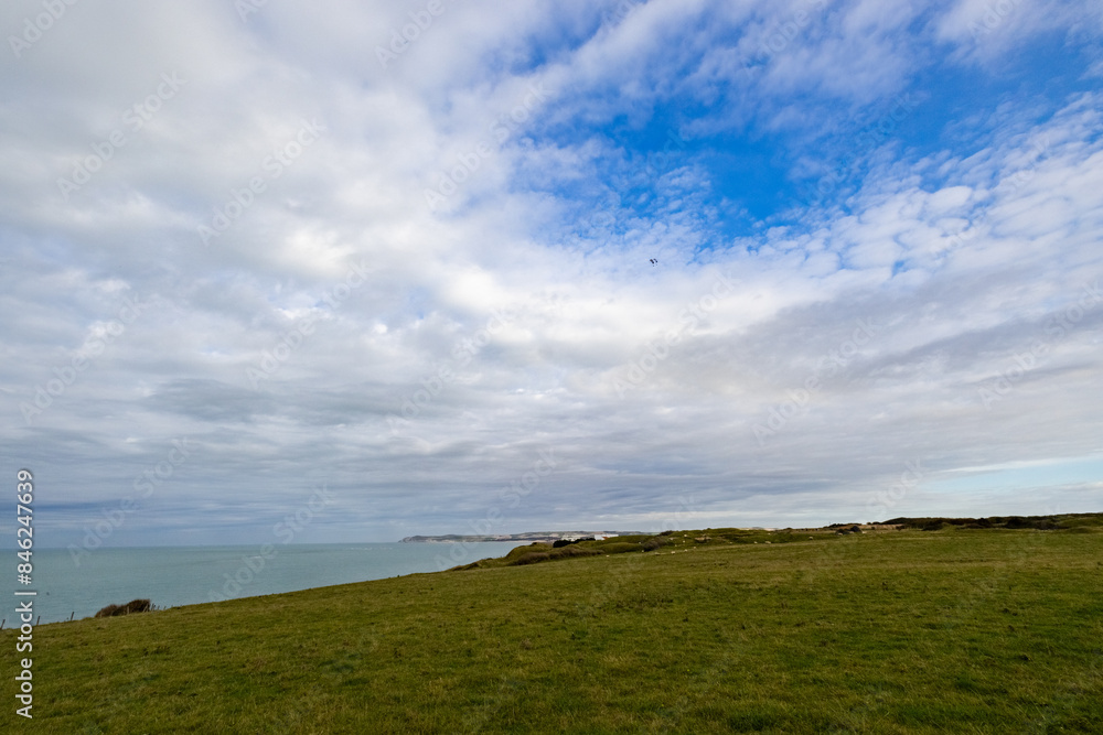 Tranquil coastal scene with a green field by the sea under a varied sky creates a peaceful atmosphere Tranquil coastal scene with a green field by the sea under a varied sky creates a peaceful atmosphere