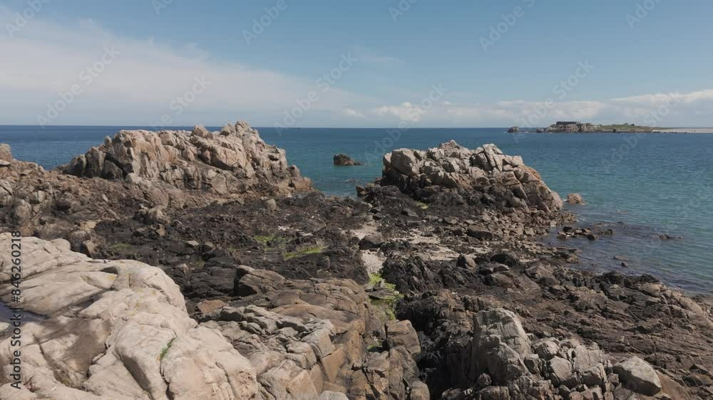 Drone flight at low tide over rocky foreshore with rockpools and birds to inlet and views across bay on bright sunny day in Guernsey.Low and slow. Drone flight at low tide over rocky foreshore with rockpools and birds to inlet and views across bay on bright sunny day in Guernsey.Low and slow.