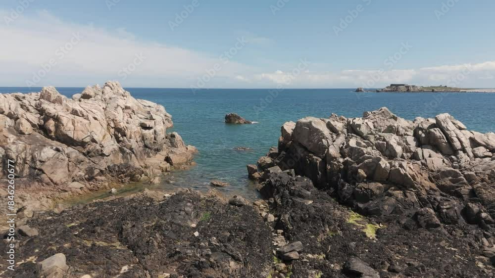 Slow forward low drone flight over rocky inlet with crystal clear sea on calm sunny day in Guernsey Slow forward low drone flight over rocky inlet with crystal clear sea on calm sunny day in Guernsey