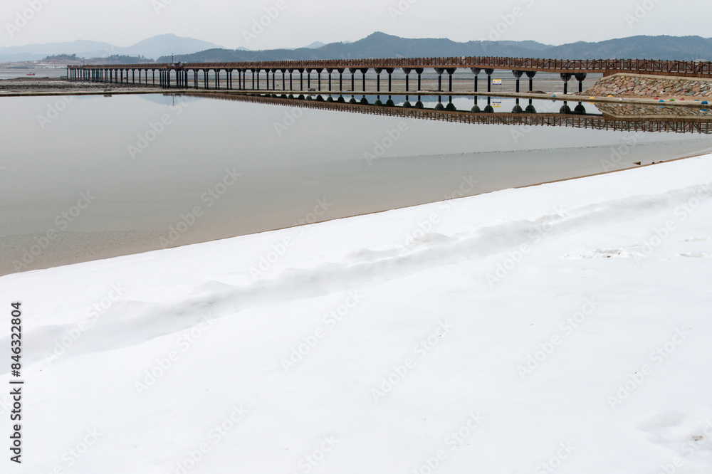 View of the wooden bridge at the snowy seaside