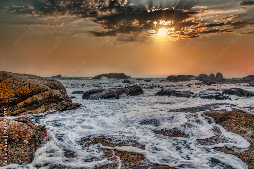 Obraz premium sea ocean white waves ,rocks at the shore , sunset sky