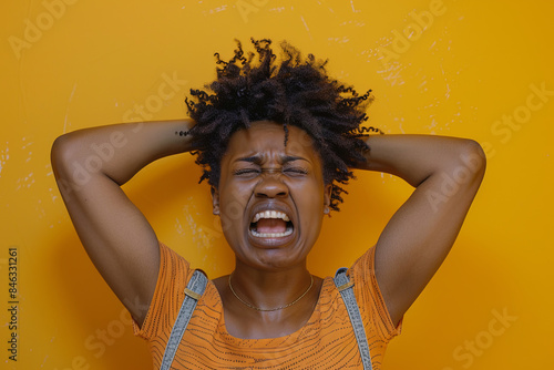 Emotional portrait of a Black woman shouting and touching her head while standing against a vibrant yellow background, conveying a sense of distress, frustration, or powerful expression