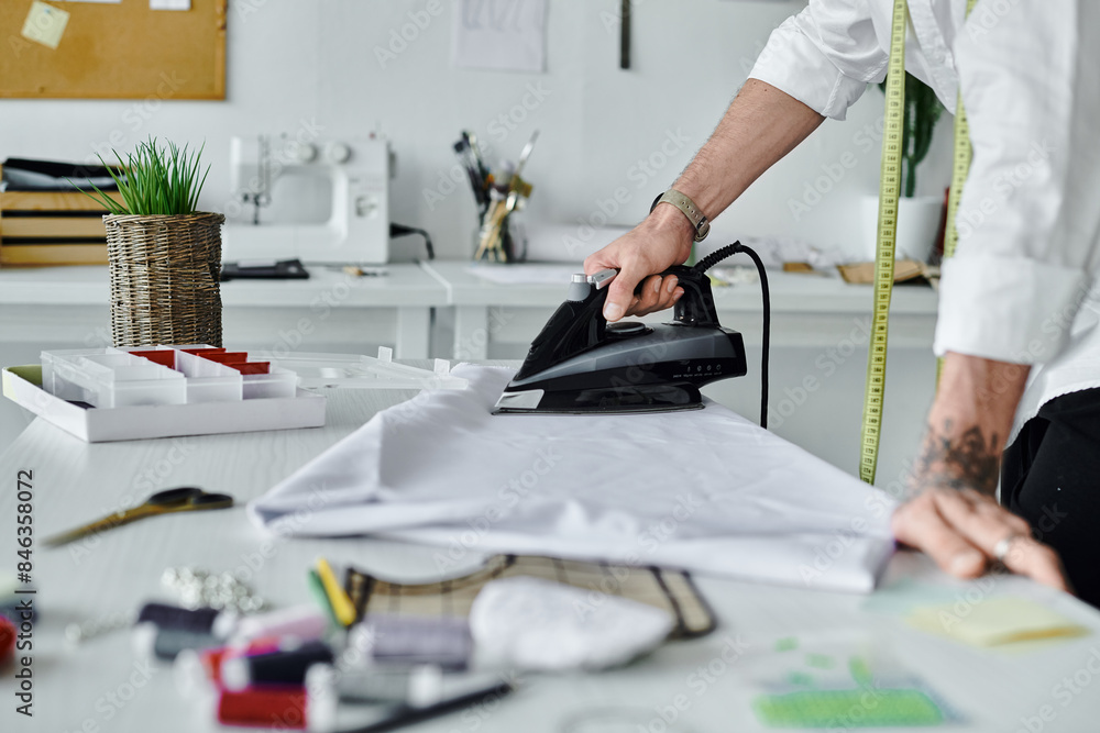 A young man meticulously irons a piece of fabric in his DIY clothing restoration atelier. A young man meticulously irons a piece of fabric in his DIY clothing restoration atelier.