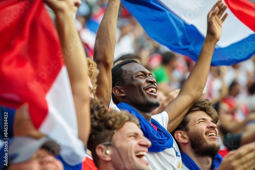 A diverse group of supporters waving the national flag and cheering, exhibiting a sense of pride and joy at a sports game