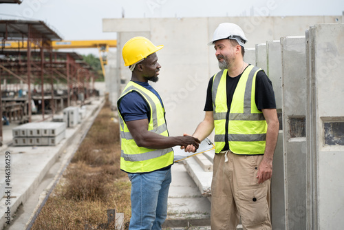 Portrait African engineer man hand shake with caucasian engineer man at precast cement outdoor factory 