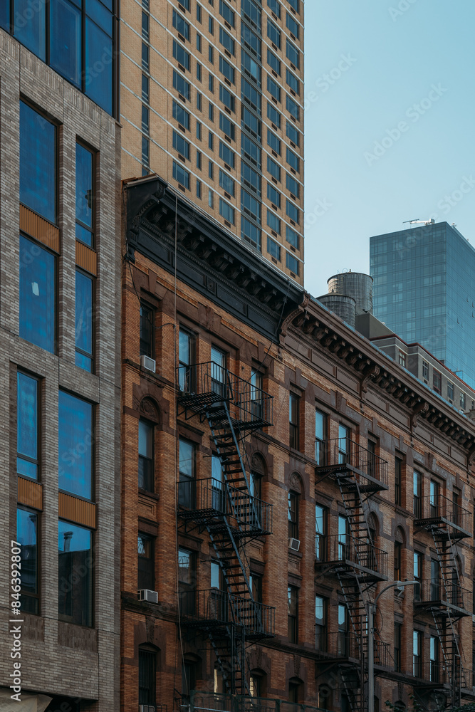 Fototapeta premium Historic New York City buildings with fire escapes and modern high-rise in background