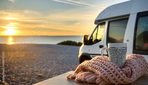 campervan with hot coffee and knitted blanket on the beach at sunset near sea view