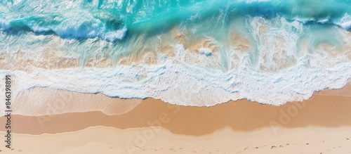 Fototapeta Naklejka Na Ścianę i Meble -  A stunning summer tropical background with beautiful sea waves seen from an aerial top view of beach sand providing ample copy space