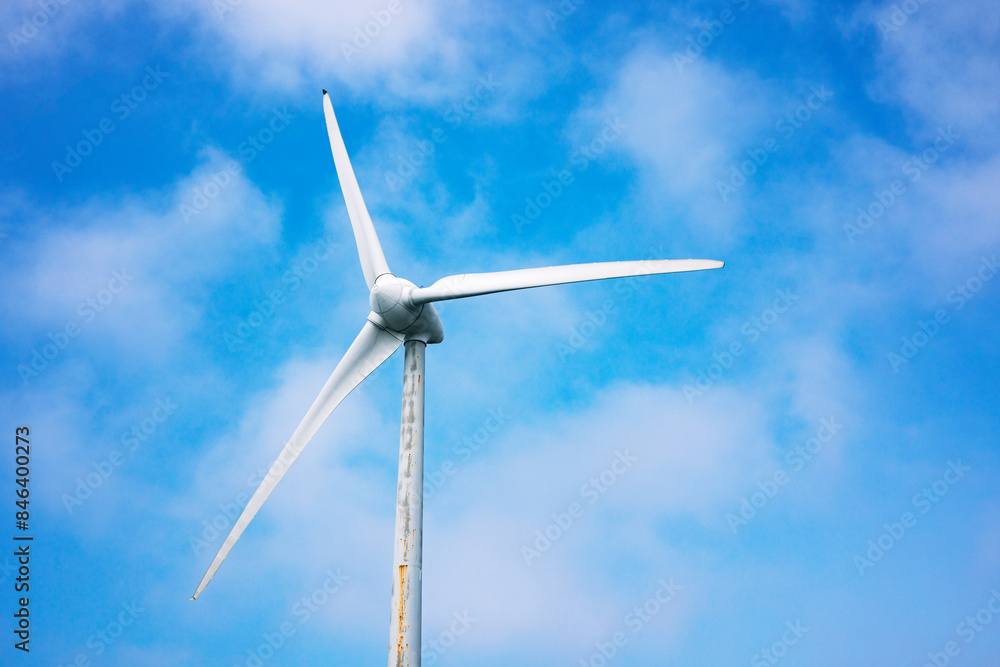White wind turbine generating electricity on blue sky White wind turbine generating electricity on blue sky