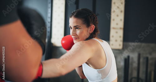 Fitness, woman and boxing in gym for training, self defence and exercise with personal trainer. Power workout, punch and female athlete with equipment for sport, learning and fighting with hard work © peopleimages.com