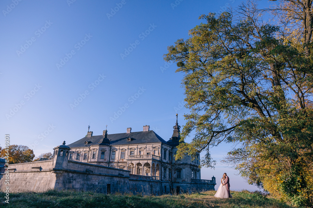 Fototapeta premium The newlyweds embrace near the ancient castle, Renaissance palaces. Photo session near the medieval castle.