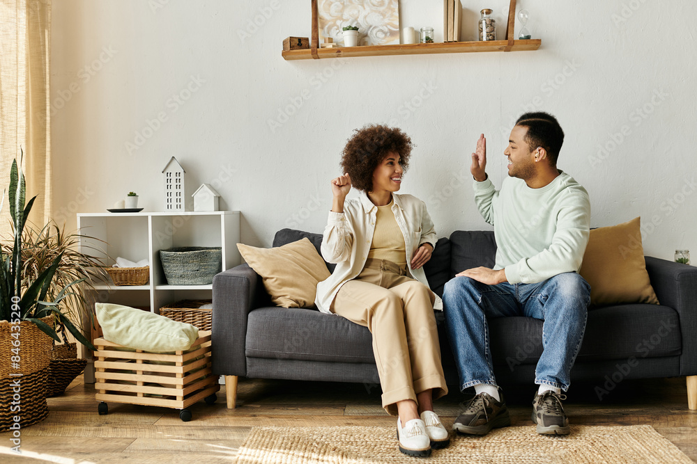 Obraz premium An African American couple sits on a couch in their home, communicating with sign language.