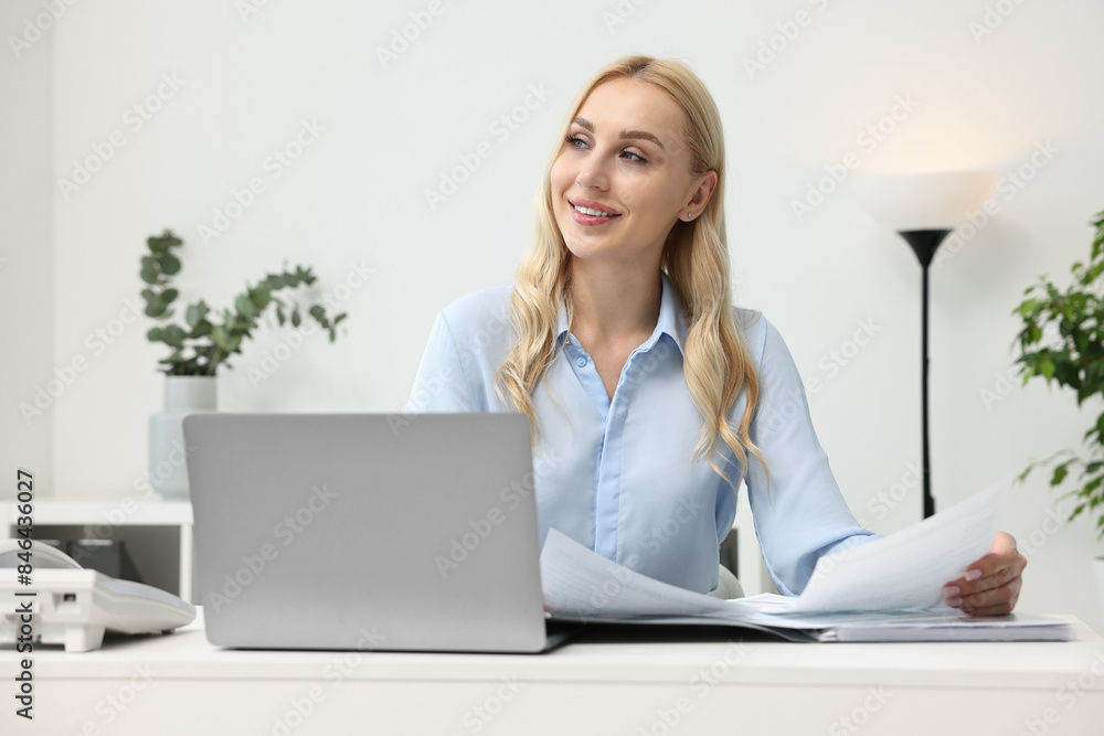Happy secretary working with documents at table in office Happy secretary working with documents at table in office