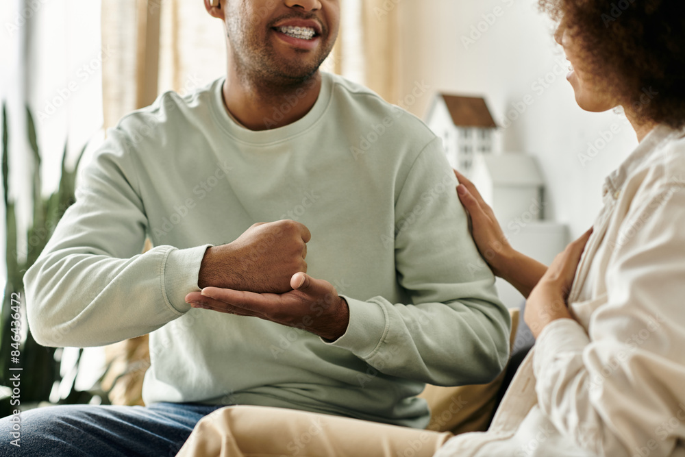 A couple in love, using sign language to communicate at home, showcasing the beauty of nonverbal expression. A couple in love, using sign language to communicate at home, showcasing the beauty of nonverbal expression.