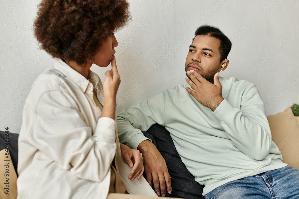 An African American couple uses sign language to communicate while relaxing at home. An African American couple uses sign language to communicate while relaxing at home.