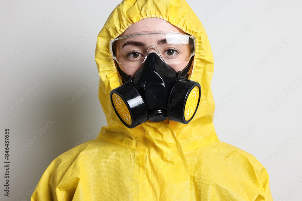 Worker in respirator, protective suit and glasses on grey background Worker in respirator, protective suit and glasses on grey background