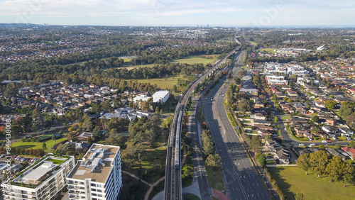 Aerial drone view above Rouse Hill Station on the metro northwest railway line, Greater Sydney, NSW Australia looking toward Kellyville as two trains pass in June 2024 