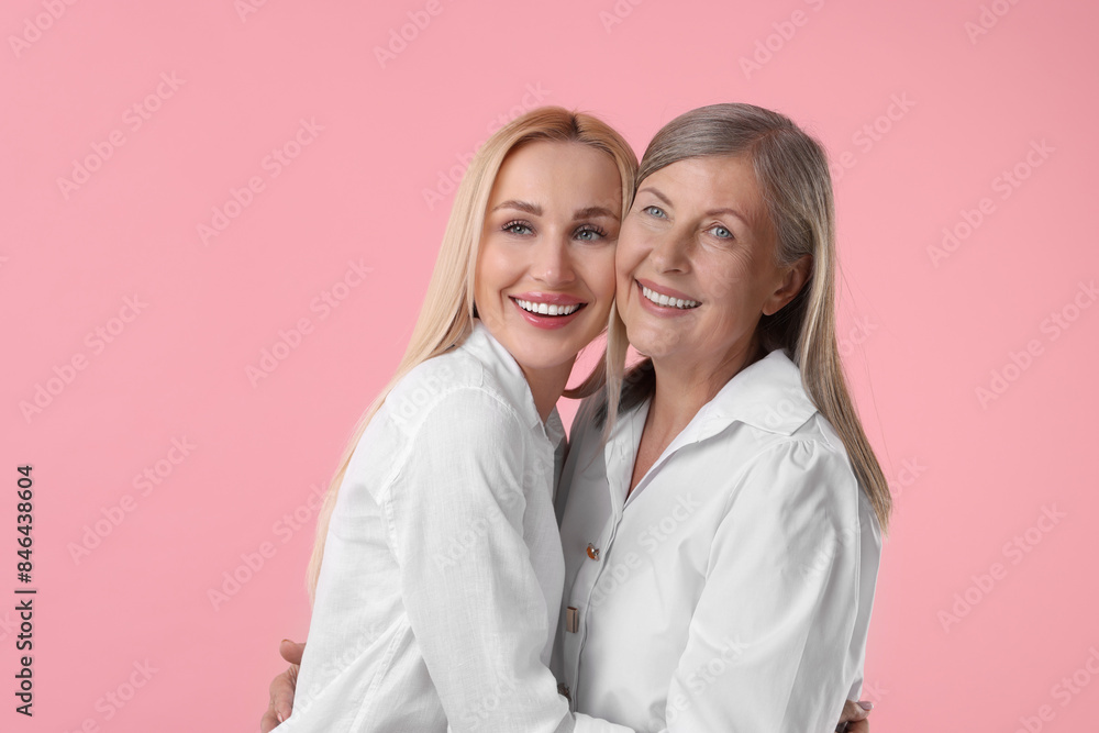 Family portrait of young woman and her mother on pink background Family portrait of young woman and her mother on pink background
