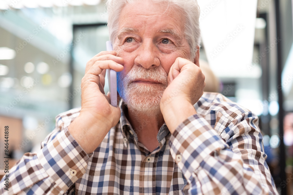 Portrait of a caucasian serious man using mobile phone - handsome bearded elderly man sitting thoughtfully while holding mobile phone Portrait of a caucasian serious man using mobile phone - handsome bearded elderly man sitting thoughtfully while holding mobile phone