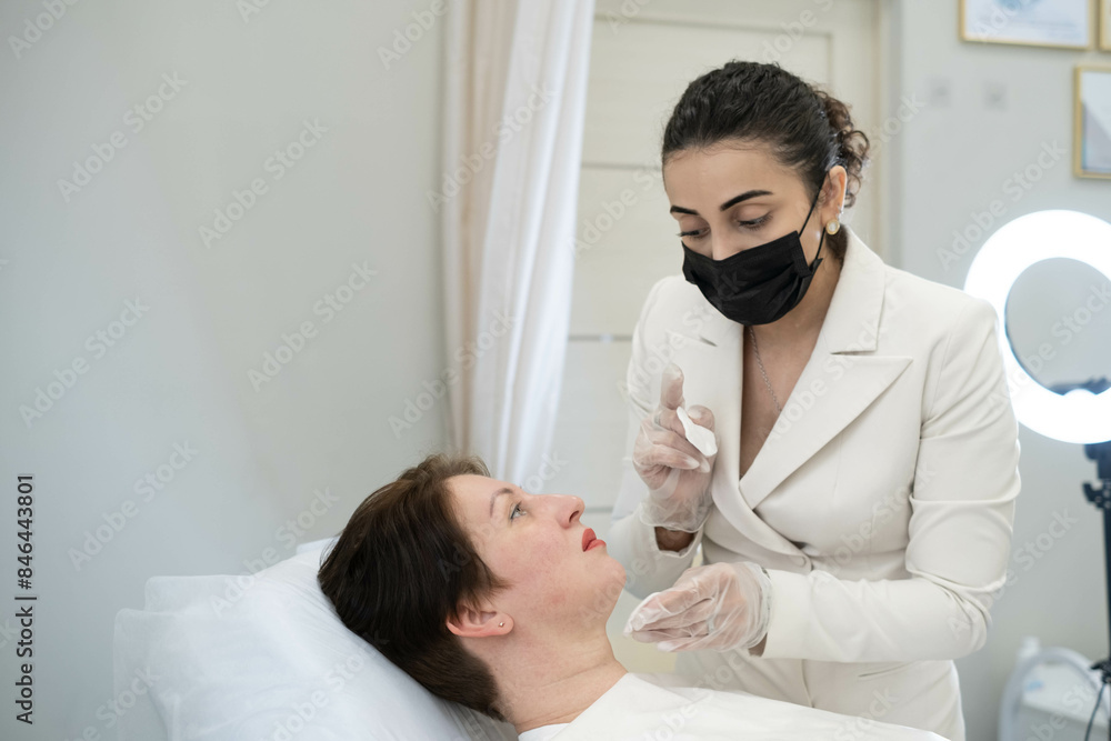 Fototapeta premium Patient and cosmetologist engage in a pre-treatment discussion, emphasizing the collaborative approach in designing personalized skincare regimens in a professional setting.