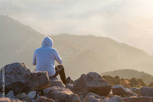 Person sits on rocks, gazing at the landscape