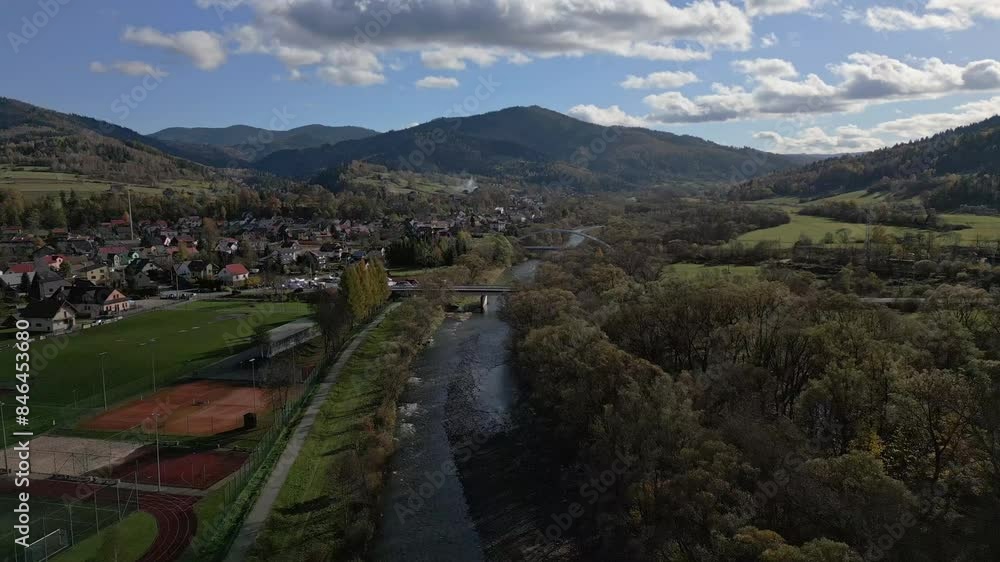 Mountain river unfolds below, flanked by lush forests on the right and the cityscape on the left. Mountain river unfolds below, flanked by lush forests on the right and the cityscape on the left.