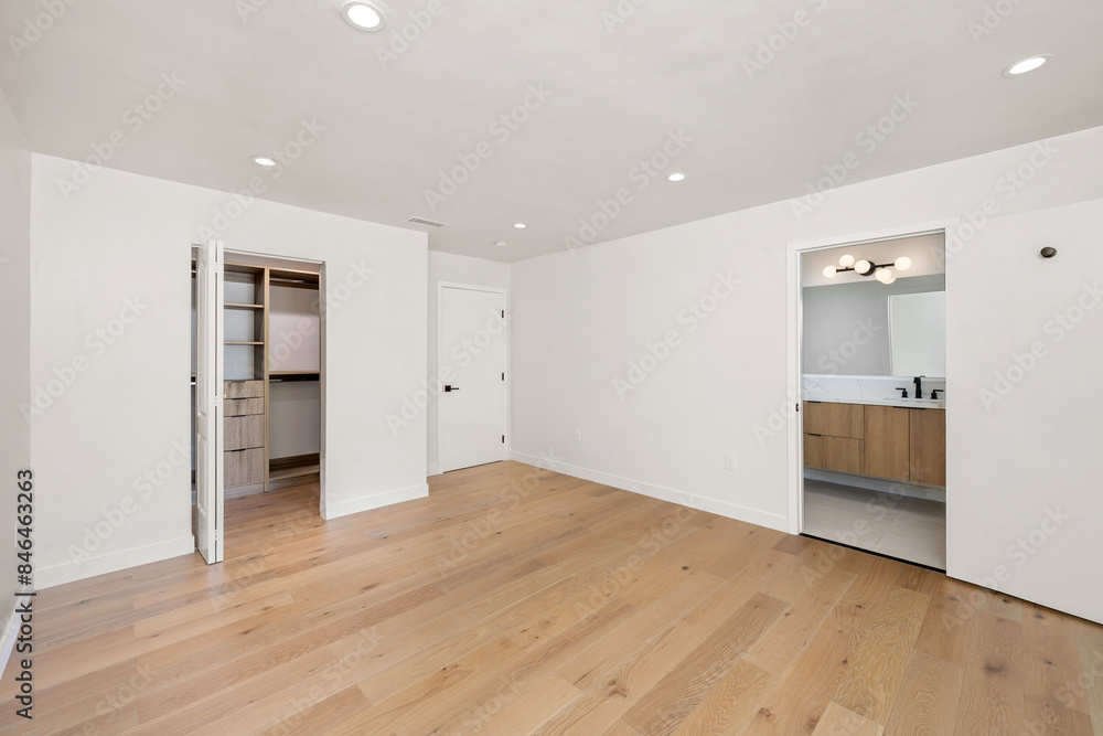 Obraz premium a small bedroom has wood floors and white walls as well as several doorways