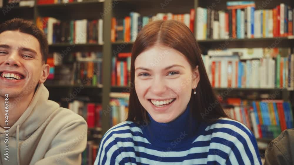 Tracking right students smiling in library with bookshelves in background. Casual and joyful atmosphere captured in candid moment. Concept of student life, friendships, and positive study environment Tracking right students smiling in library with bookshelves in background. Casual and joyful atmosphere captured in candid moment. Concept of student life, friendships, and positive study environment