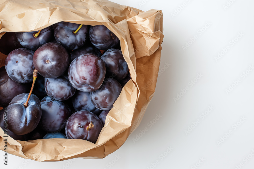 Obraz premium Fresh plums are placed in a paper bag on a white background. The concept of grocery shopping, organic products. Plums studio image. Full sack of plums on a white background.