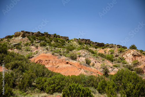 a green hillside is topped by hills and a clear blue sky