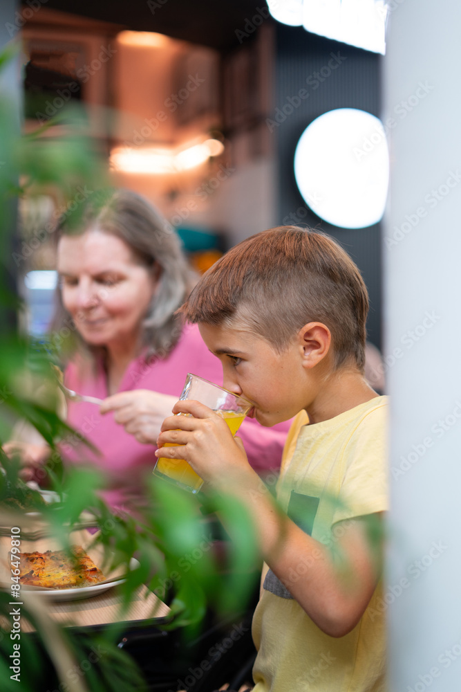 Boy drinking a soft drink with his grandmother in a restaurant Boy drinking a soft drink with his grandmother in a restaurant
